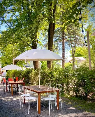a wooden table with chairs and an umbrella at Le Boulevard par Maison Dudley in Lac-Mégantic
