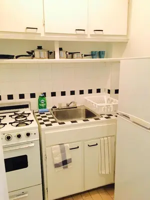 a white kitchen with a sink and a stove at Stylish Montreal Apartment: Comfortable Stay in the Golden Square Mile in Montréal