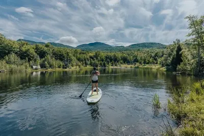 a woman on a paddle board on a river at Cabin Zoobox 47 in Eastman