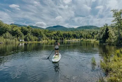 a woman on a paddle board on a river at Cabin Zoobox 56 in Eastman