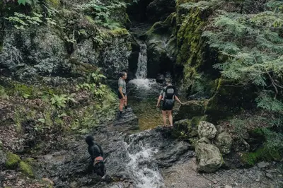 three people standing in a stream in a waterfall at Cabin Zoobox 56 in Eastman
