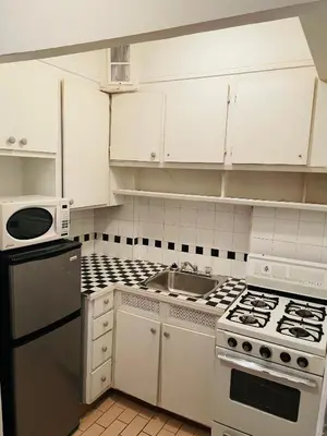 a white kitchen with a stove and a sink at Stylish Montreal Apartment: Comfortable Stay in the Golden Square Mile in Montréal