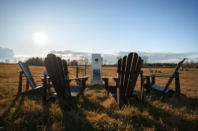 two adirondack chairs and a table in a field at MiniBora Le lichen - Cantons-de-l'Est in Bury