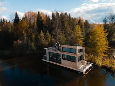 two people standing on a house on a dock in the water at MiniBora Le marin - Cantons-de-l'Est in Bury