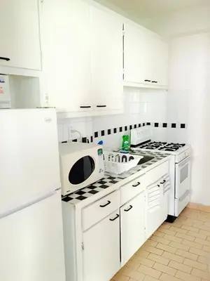 a white kitchen with white cabinets and a stove top oven at Stylish Montreal Apartment: Comfortable Stay in the Golden Square Mile in Montréal