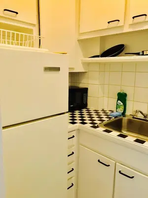 a white kitchen with a sink and a stove at Stylish Montreal Apartment: Comfortable Stay in the Golden Square Mile in Montréal