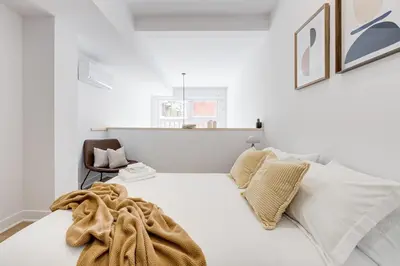 a white bedroom with a bed and a chair at Le Mile End by M11 - Luxury 1BDR Loft with Sofa Bed in Montréal
