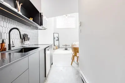 a kitchen with white cabinets and a sink at Le Mile End by M11 - Modern & Stylish 1BDR with Sofa Bed in Montréal