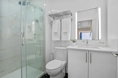 a white bathroom with a toilet and a shower at Central King Studio in Montréal
