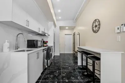 a kitchen with white cabinets and a clock on the wall at DownTown King Suite in Montréal