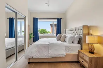 a bedroom with a large bed with blue curtains at City Center King Suite in Montréal