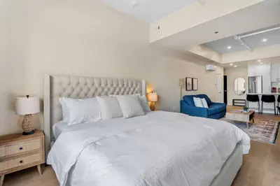 a bedroom with a large white bed and a blue chair at City Center King Suite in Montréal