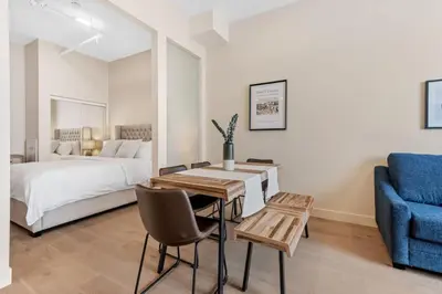 a bedroom with a bed and a table and a blue chair at Downtown 2BR Suite in Montréal