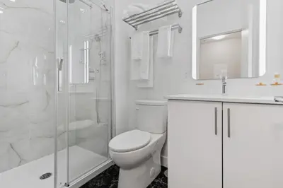 a white bathroom with a toilet and a shower at City Center 2BR Condo in Montréal