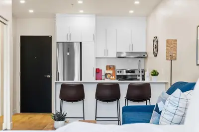 a kitchen with three chairs and a counter with a refrigerator at Central Studio in Montréal