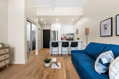 a living room with a blue couch and a kitchen at Central Studio in Montréal