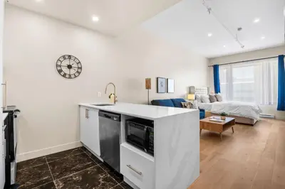 a kitchen and living room with a couch and a clock at Central Studio in Montréal