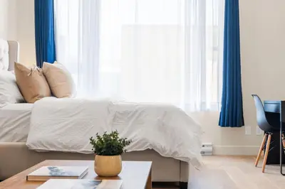 a bedroom with a white bed with blue curtains at Central Studio in Montréal