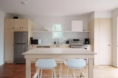 a kitchen with a table and three white chairs at Chalet 1 OST Shefford in Shefford