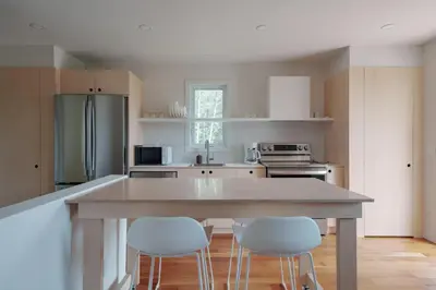 a kitchen with a large island with four white chairs at Chalet 5 OST Shefford in Shefford