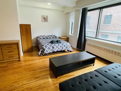a room with two beds and a table in it at Stylish Montreal Apartment Comfortable Stay in the Golden Square Mile in Montréal