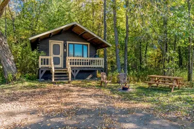 a cabin in the woods with a picnic table and a bench at Chalet 3 - Domaine de l Archipel in Sorel