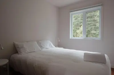 a white bed in a white room with a window at Chalets OST Shefford FORFAIT GROUPE in Shefford