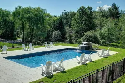 a swimming pool with chairs and a fountain at 853 condo in Bromont Vieux Village mountain view in Bromont