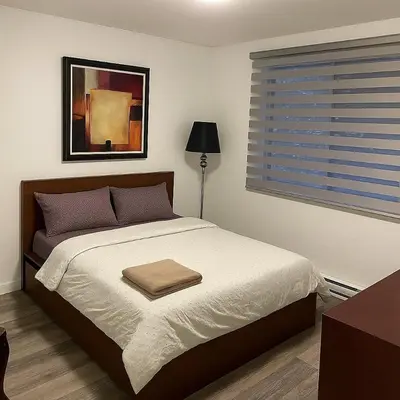 a bedroom with a large bed with a window and a table at Bright Renovated 4BR, Heart of Côte-des-Neiges, Montreal in Montréal