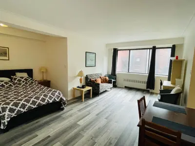 a bedroom with a bed and a couch and window at Stylish Montreal Apartment Comfortable Stay in the Golden Square Mile in Montréal