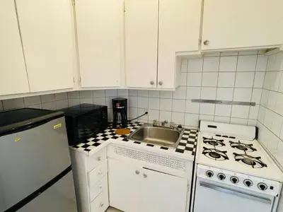 a white kitchen with a sink and a stove at Stylish Montreal Apartment Comfortable Stay in the Golden Square Mile in Montréal
