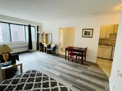 a living room with a table and a kitchen at Stylish Montreal Apartment Comfortable Stay in the Golden Square Mile in Montréal
