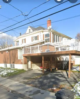 a large house with a large deck in front of it at le vétérans centrale in Lac-Mégantic