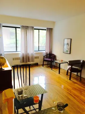 a living room with a table and chairs and windows at Stylish Montreal Apartment Comfortable Stay in the Golden Square Mile in Montréal