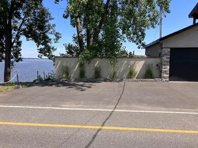a parking lot in front of a house with a lake at Modern apartment with magnificent views in Vaudreuil-Dorion