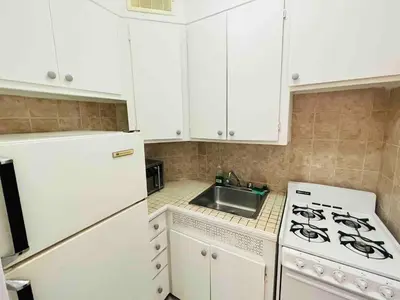 a kitchen with white cabinets and a stove and a sink at Modern City Apartment Living in the Golden Square Mile in Montréal
