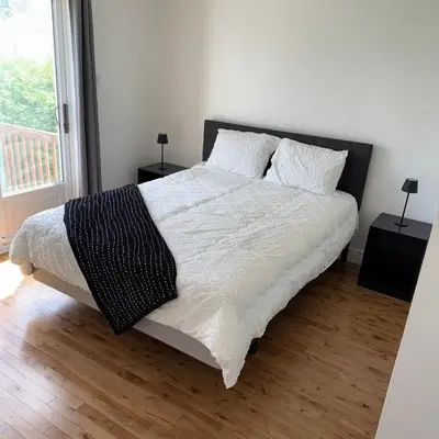 a bedroom with a large bed with white sheets and pillows at Chambre queen near Montreal in Sainte-Catherine