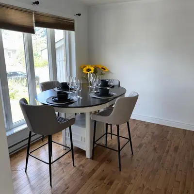 a dining room with a table with chairs and flowers at Chambre queen near Montreal in Sainte-Catherine