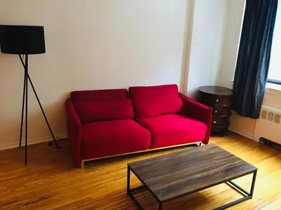 a red couch in a living room with a table at Modern City Studio Living in the Golden Square Mile in Montréal