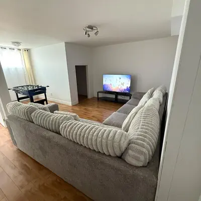 a living room with a couch and a flat screen tv at Apartment 3 chambres near Montréal in Sainte-Catherine