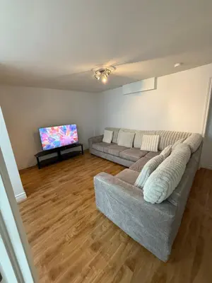 a living room with a couch and a flat screen tv at Chambre à louer proche de Montréal in Sainte-Catherine