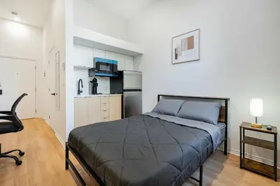 a bedroom with a bed and a small kitchen at Beautiful 3 person 2 Beds Studio with parking near downtown Montreal in Montréal