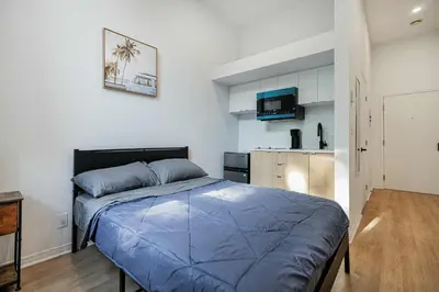 a bedroom with a blue bed and a kitchen at Beautiful 3 person 2 Beds Studio with parking near downtown Montreal in Montréal