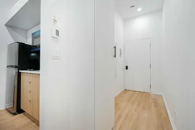 a white room with a kitchen and a refrigerator at Escape studio with parking near downtown Montreal in Montréal