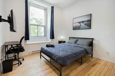 a bedroom with a bed and a desk and a chair at Chic Bright Apartment with Parking Near downtown Montreal in Montréal