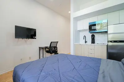 a bedroom with a blue bed and a kitchen at Chic Bright Apartment with Parking Near downtown Montreal in Montréal