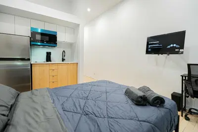 a bedroom with a bed and a refrigerator and a tv at Cozy Studio Near Downtown Montreal with Parking in Montréal
