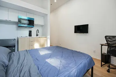 a bedroom with a blue bed and a kitchen at Cozy Studio Near Downtown Montreal with Parking in Montréal