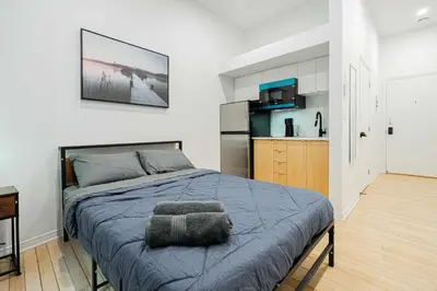a bedroom with a bed and a kitchen at Cozy Studio Near Downtown Montreal with Parking in Montréal