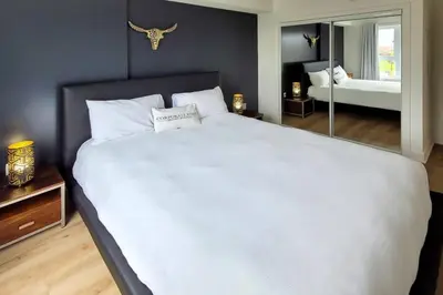 a large white bed in a bedroom with a mirror at Corporate Stays Blum 2 Bedrooms in Brossard